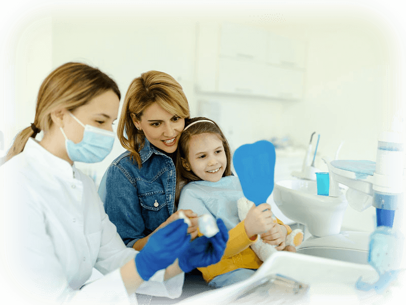 Child smiling with mother and dentist during a children's dentistry visit