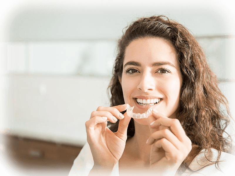 Patient holding clear Invisalign retainers in a modern dental office